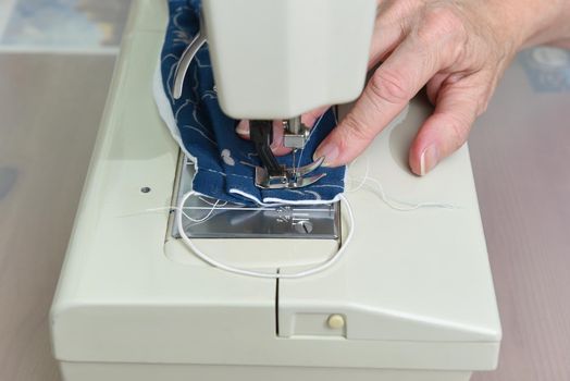 Closeup of a woman’s hands sewing a homemade COVID-19 face mask, to ease the shortage of available protection for the public.