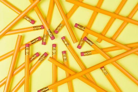 Back to School theme: Top view of a group of pencils on a yellow background filling the frame.