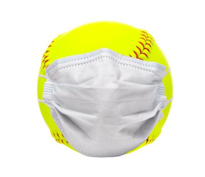 Sports and Covid-19-Concept. Yellow softball with a surgical mask on white background.