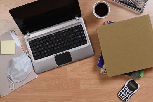 Working from home concept. Laptop, Cell Phone, Books, Coffee and other items used to telecommute during the COVID-19 stay at home lockdown.