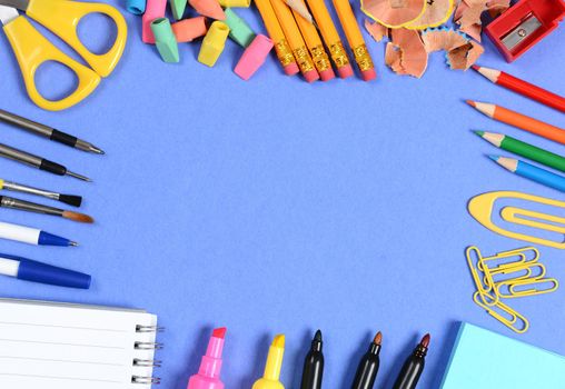 School supplies arranged on the outer edge of a blue background. Center is blank for your own copy.
