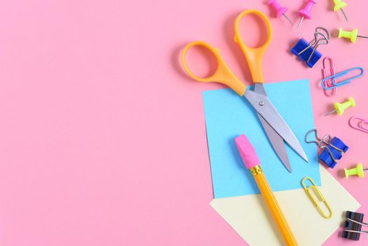 Back to School Concept: Overhead flat lay arrangement of school supplies on a pink background.