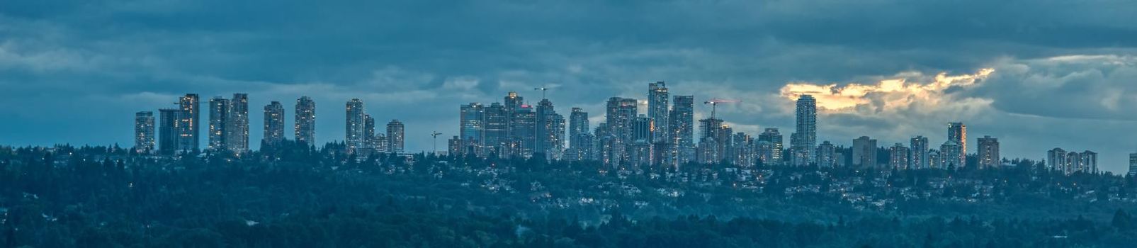 Panoramic scenery view of Metrotown cityscape over Burnaby lake on cloudy sky background