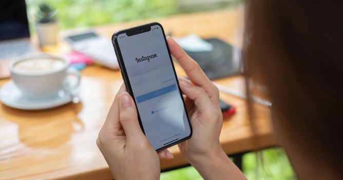 CHIANG MAI, THAILAND - JUNE 6, 2021 : Woman hand holding Iphone X with Instagram application on the screen