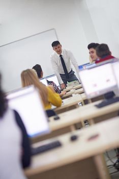 group of students with teacher in computer lab classrom learrning lessons,  get help and support