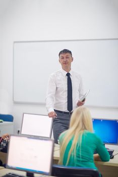 group of students with teacher in computer lab classrom learrning lessons,  get help and support