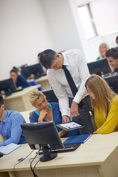 group of students with teacher in computer lab classrom learrning lessons,  get help and support