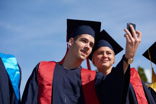 Capturing a happy moment.Students group  college graduates in graduation gowns  and making selfie photo