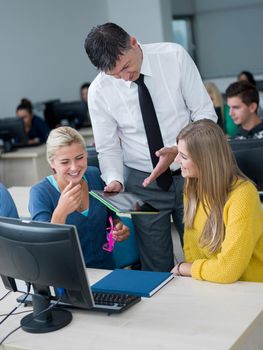 group of students with teacher in computer lab classrom learrning lessons,  get help and support