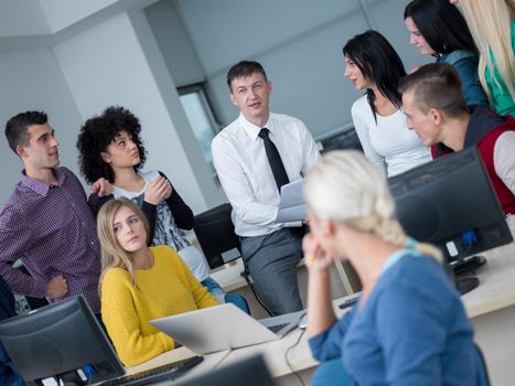 group of students with teacher in computer lab classrom learrning lessons,  get help and support