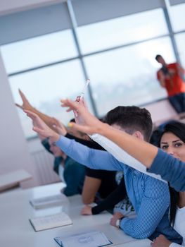 students group raise hands up in classroom