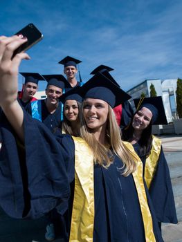 Capturing a happy moment.Students group  college graduates in graduation gowns  and making selfie photo