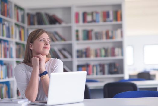 female student study in school library, using laptop and searching for informations on internet