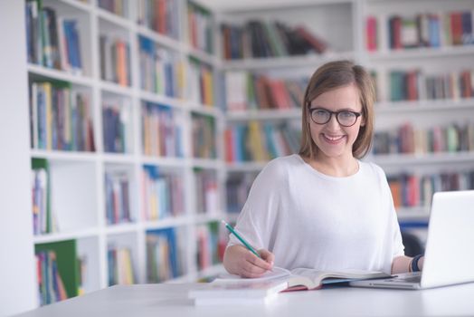 female student study in school library, using laptop and searching for informations on internet