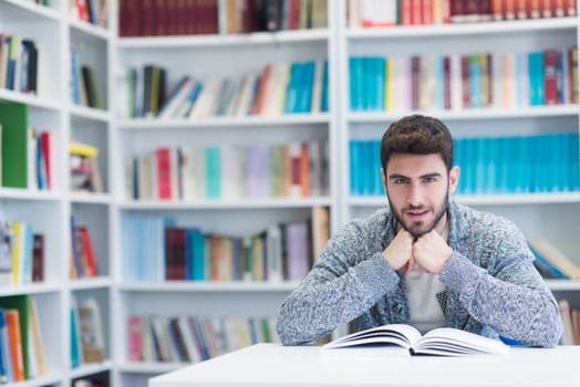 Portrait of happy student while reading book in school library. Study lessons for  exam. Hard worker and persistance concept.