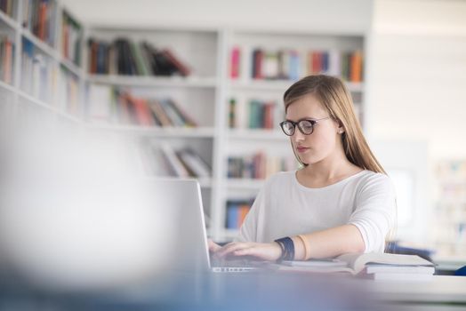 female student study in school library, using laptop and searching for informations on internet