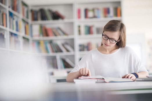 female student study in school library, using laptop and searching for informations on internet