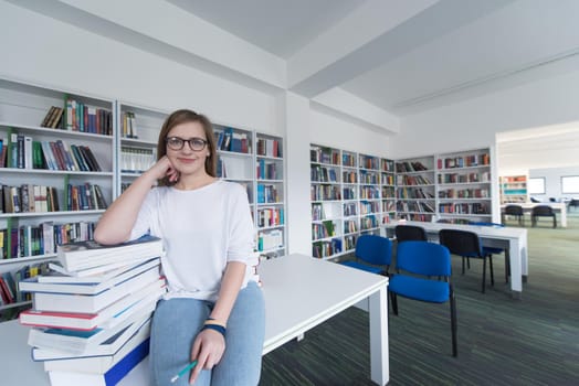 female student study in school library, using tablet and searching for information’s on internet. Listening music and lessons on white headphones