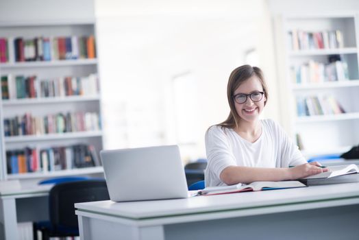 female student study in school library, using laptop and searching for informations on internet