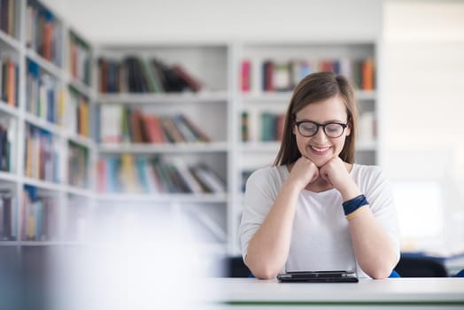 female student study in school library, using tablet  and searching for informations on internet