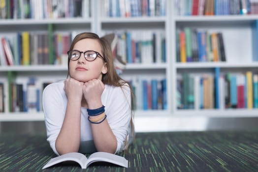 female student study in school library, using tablet and searching for information’s on internet. Listening music and lessons on white headphones