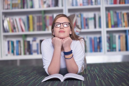 female student study in school library, using tablet and searching for information’s on internet. Listening music and lessons on white headphones