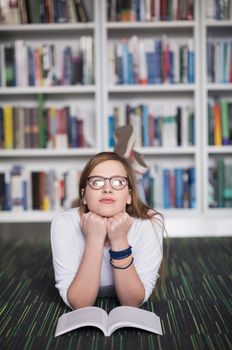 female student study in school library, using tablet and searching for information’s on internet. Listening music and lessons on white headphones