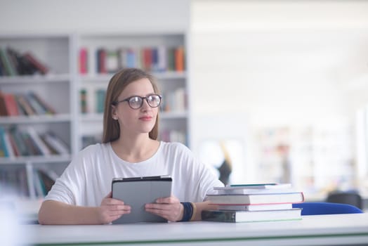 female student study in school library, using tablet  and searching for informations on internet