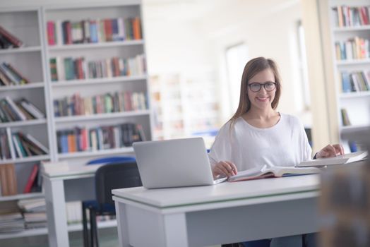 female student study in school library, using laptop and searching for informations on internet