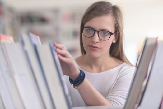 portrait of smart looking famale student girl  in collage school library,  selecting book to read from bookshelf