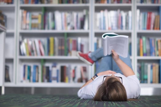 female student study in school library, using tablet and searching for information’s on internet. Listening music and lessons on white headphones