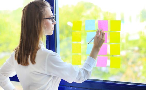 Attractive woman writing on stickers at office