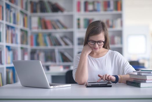 female student study in school library, using laptop and searching for informations on internet