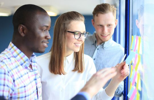 young creative startup business people on meeting at modern office making plans and projects with post stickers on glass