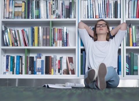 female student study in school library, using tablet and searching for information’s on internet. Listening music and lessons on white headphones