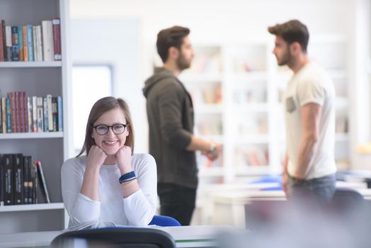 female smart looking student study in school library, group of students in background