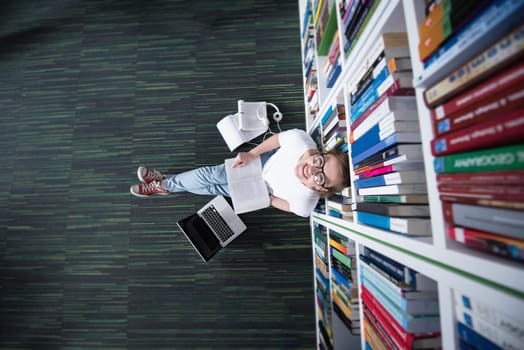 female student study in school library, using tablet and searching for information’s on internet. Listening music and lessons on white headphones