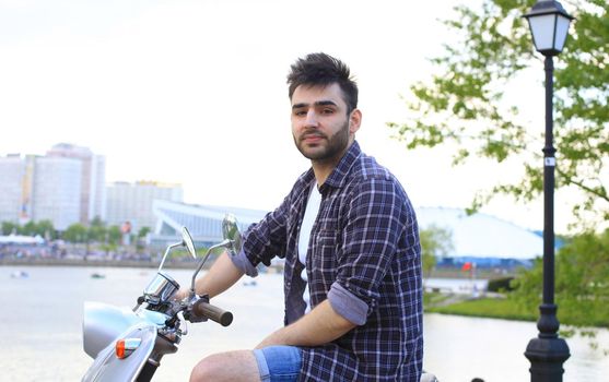 fashionable young man riding a vintage scooter in the street