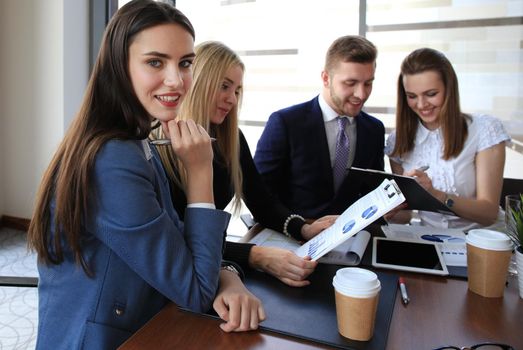 A group of business people at a meeting on the background of office. Focus on a beautiful brunette
