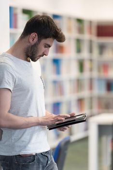 student preparing exam and learning lessons in school library, making research on tablet  and browse internet