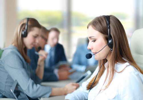 Portrait of call center worker accompanied by her team. Smiling customer support operator at work.