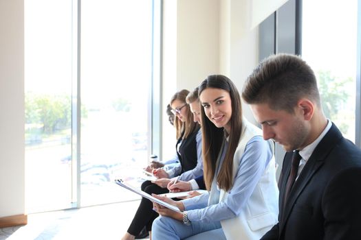 Smiling businesswoman looking at camera at seminar with her colleagues near by