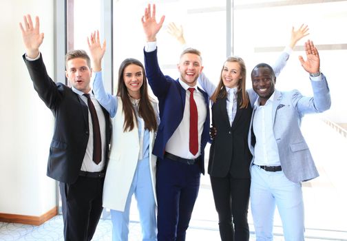 Portrait of successful business group waving hands in office