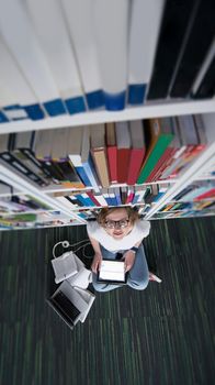 female student study in school library, using tablet and searching for information’s on internet. Listening music and lessons on white headphones