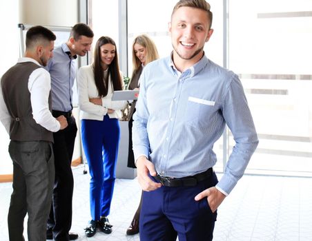 Businessman with colleagues in the background in office.