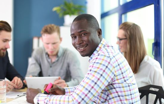 Portrait of smiling African American business man with executives working in background