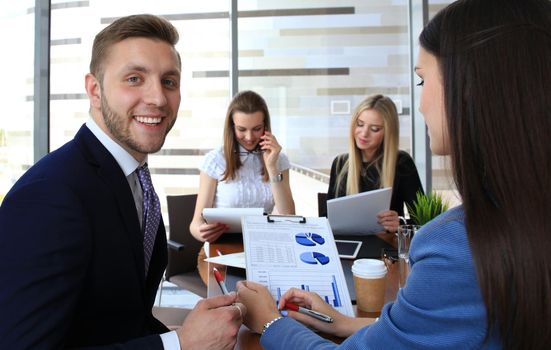 Happy smart business man with team mates discussing in the background