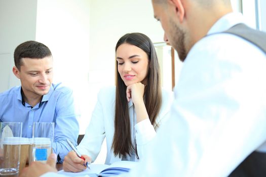 A group of business people at a meeting on the background of office. Focus on a beautiful brunet