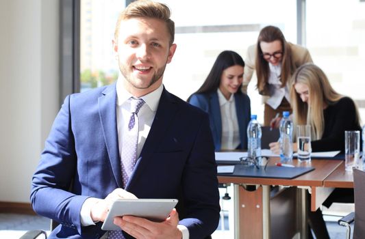 Happy smart business man with team mates discussing in the background