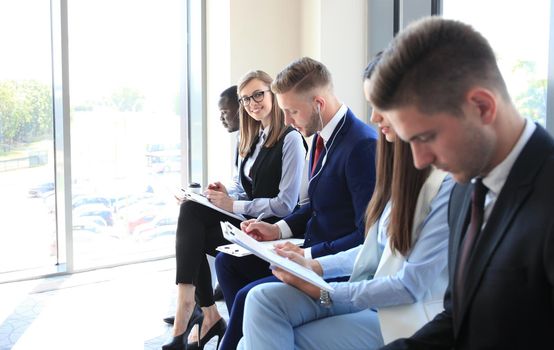 Smiling businesswoman looking at camera at seminar with her colleagues near by